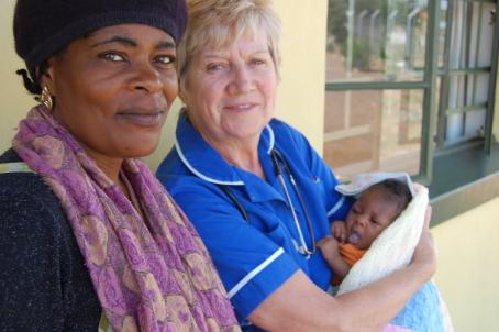 Linda with a baby that was born at the clinic with the mother who had come to visit the doctor for a check up.